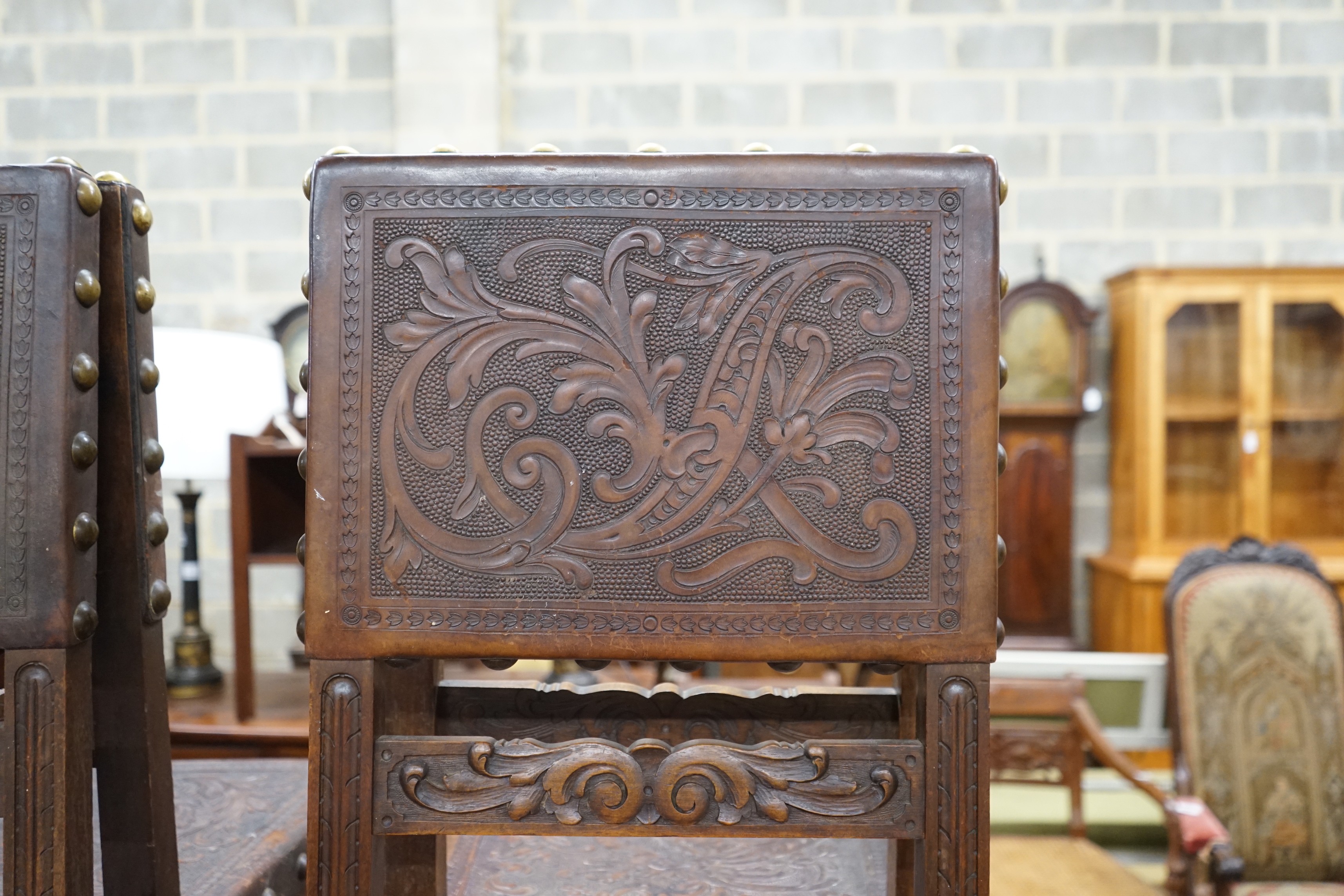 A set of six 18th century style brass studded carved oak and embossed leather dining chairs